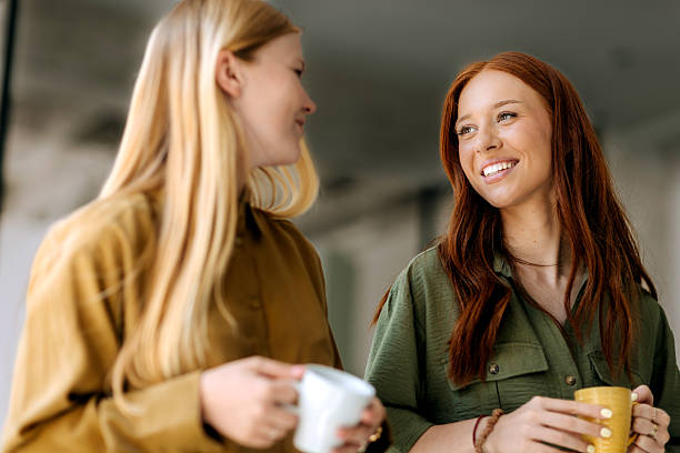 istock Two young female colleagues walking with coffee cups in office 2223352139
