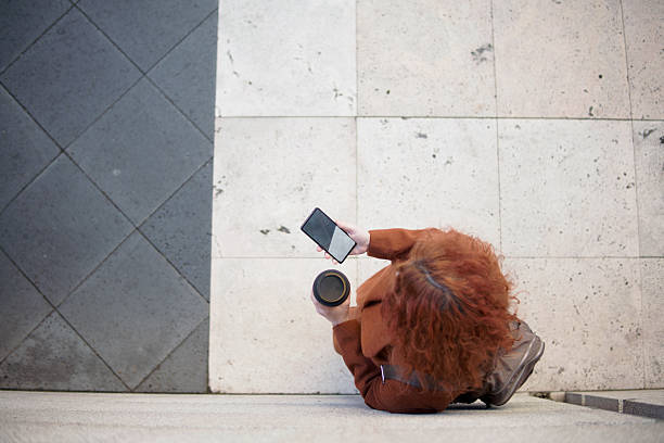istock Businesswoman using smartphone and holding coffee outside office building 2223353067