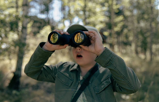Portrait of a bird enthusiast bird watching in a park or a forest. Equipped with binoculars looking for sightings of rare and exciting bird species