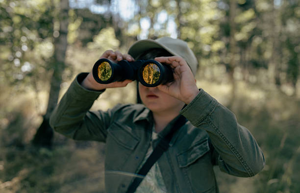 istock Boy backpacking in the summer forest. Bird watching adventure. Looking through binoculars. Birding 2223354955