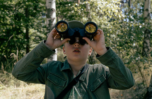 Portrait of a bird enthusiast bird watching in a park or a forest. Equipped with binoculars looking for sightings of rare and exciting bird species
