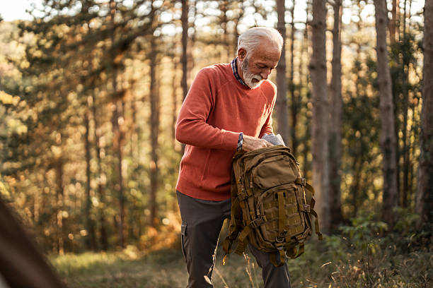 istock Senior Man Exploring Outdoors and Preparing Gear in a Sunlit Forest 2223355368