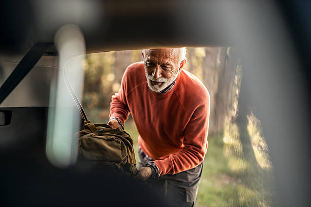 istock Senior Man Unpacking Camping Gear from Car in Forest Setting 2223355374