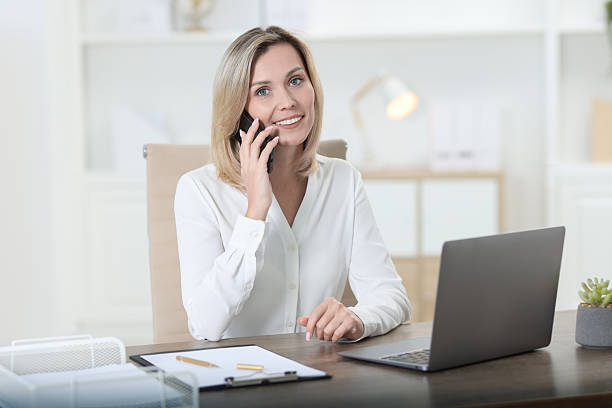 istock Businesswoman talking on smartphone at table in office 2223355470