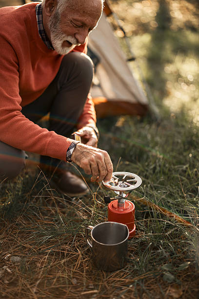 istock Elderly Man Camping and Cooking Outdoors in a Scenic Forest Setting 2223355478