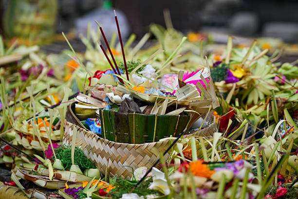 Close-up of colorful Balinese Hindu offerings (canang sari) made of flowers, leaves, and incense sticks, used in daily rituals in Bali, Indonesia
