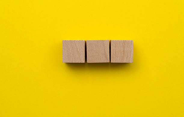 istock Three wooden cubes on yellow background 2223358463