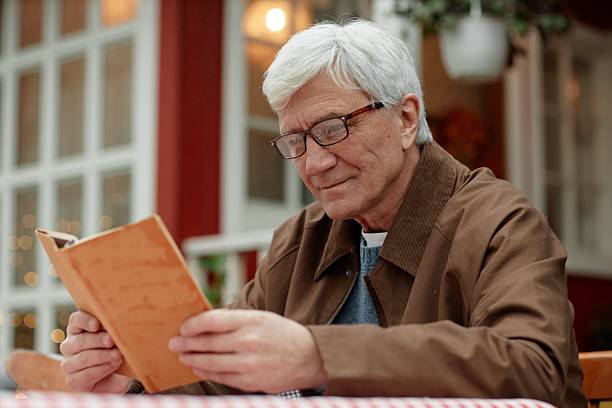 istock Senior Caucasian Man Reading Book Outdoors in Village Setting 2223360381