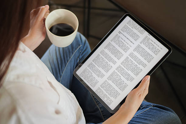 istock woman hand holding coffee cup and tablet, reading text on tablet device with a touchscreen interface for digital press article feed in the morning. mockup media publication website on portable tablet 2223360936