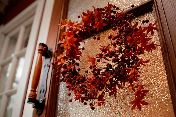 Autumn wreath with orange leaves and red berries hanging on wooden door, capturing seasonal village decor, closeup of handmade arrangement emphasizing rustic countryside tradition
