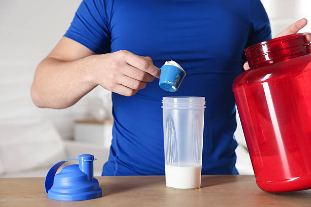 istock Making protein cocktail. Man adding powder into shaker at wooden table, closeup 2223363944