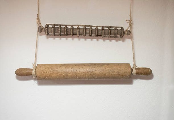 two old wooden rolling pins hanging on the wall: one smooth for the pastry the other shaped for ravioli