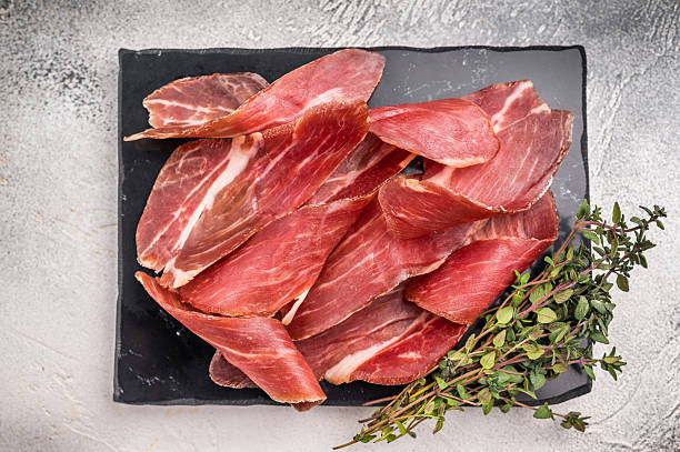 istock Sliced Speck bacon, Italian cured meat. grey background. top view 2223370685