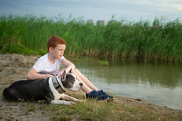Teenager and dog lying together on a sandy beach