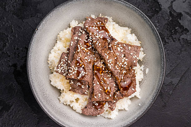 Yakiniku, wagyu marbled beef cuts and rice in a bowl. A culinary journey that captures the essence of Japanese grilling traditions. black background. top view
