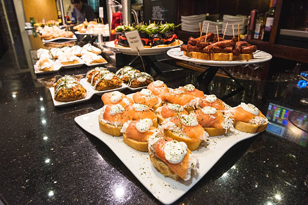 A vibrant selection of pintxos, traditional Basque tapas, beautifully displayed on a restaurant counter. The variety includes seafood and meat dishes, perfect for a gourmet culinary experience, showcasing Spanish hospitality and cuisine.