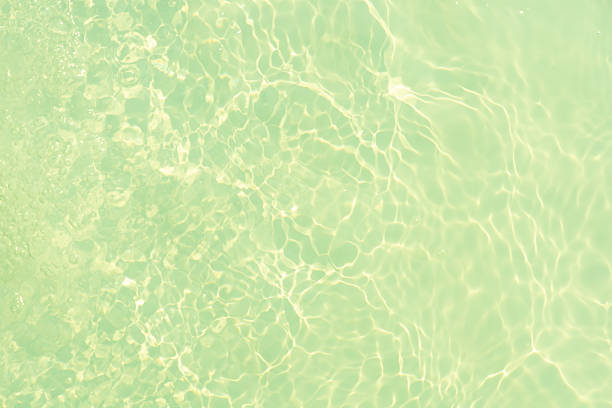 Blue water with ripples on the surface. Defocus blurred transparent blue colored clear calm water surface texture with splashes and bubbles. Water waves with shining pattern texture background.