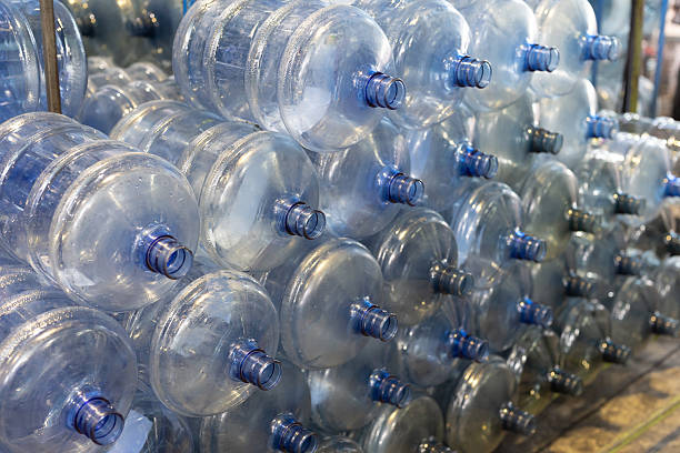 istock Drinking water production plant. 20 liter empty bottled water in storage warehouse. Manufacturers of 20 Litres Bottles. 20 liter bottled water filling machine plant 2223395998