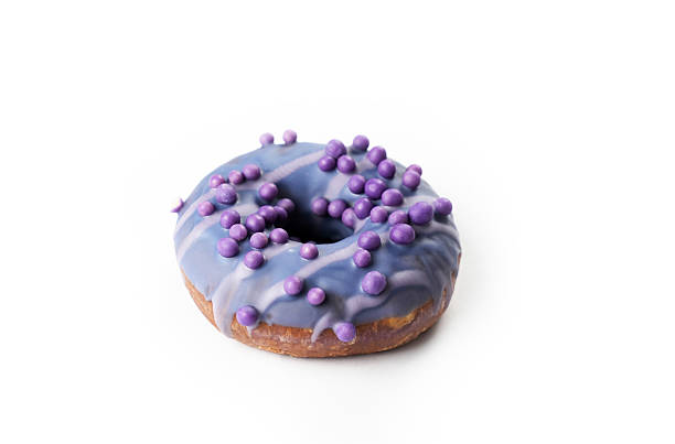 istock Unique purple donut decorated with small edible spheres on a simple background 2223396863