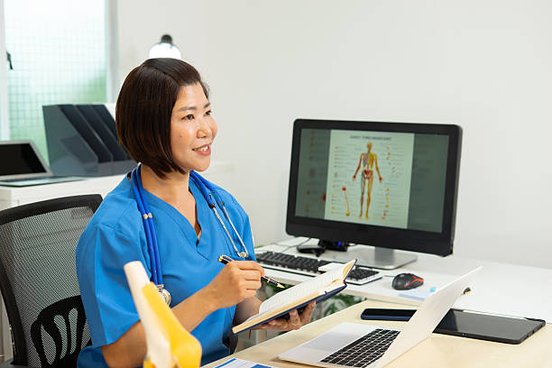 istock Medical professional writing notes with stethoscope and anatomy chart on computer 2223401785