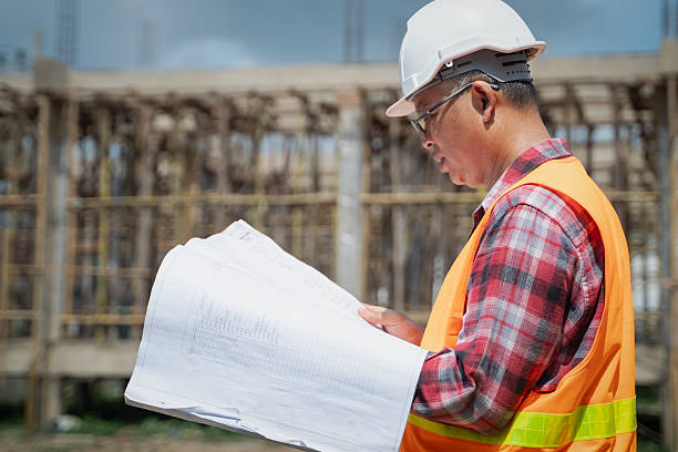 istock Asian male engineer supervising construction work inspecting blueprints at construction site 2223405437