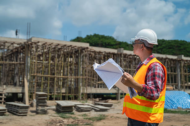 istock Asian male engineer supervising construction work inspecting blueprints at construction site 2223405440