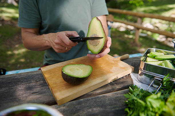 istock Person Preparing Fresh Avocado Outdoors on a Wooden Table 2223414500
