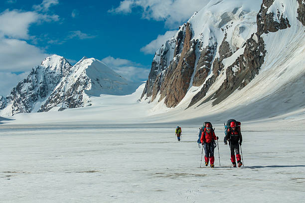 Tian-Shan, Kyrgyzstan, July 7, 2021: Alpine climbers rope team on glacier high altitude cold snow Tian-Shan mountain range climbing between crevasses use crampons ice axe. Narrow snow ridge