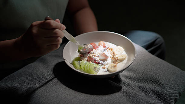Asian woman eating yogurt with fruit