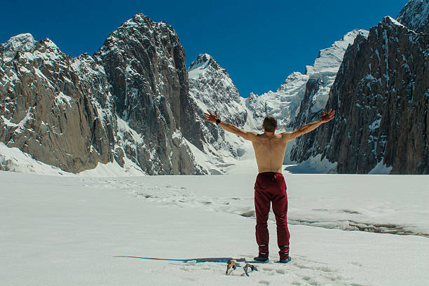 Tian-Shan, Kyrgyzstan, July 7, 2021: Alpine climbers rope team on glacier high altitude cold snow Tian-Shan mountain range climbing between crevasses use crampons ice axe. Narrow snow ridge