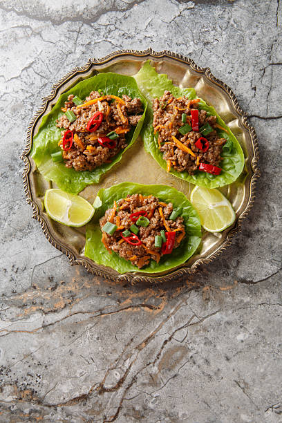 Asian Lettuce Wraps are filled with saucy, gingery beef and vegetables close-up on the plate. Vertical top view