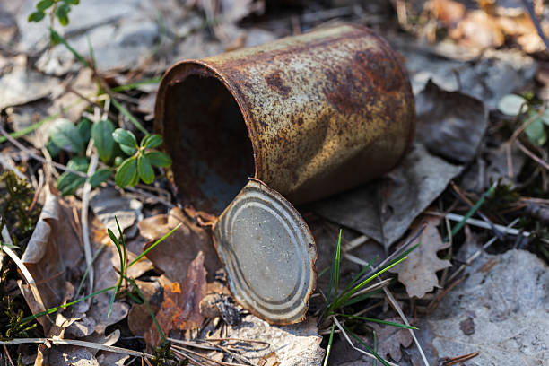 Rusty abandoned metallic can is on the ground surrounded by leaves and grass. The image conveys a sense of neglect and decay, highlighting waste management and environmental concerns