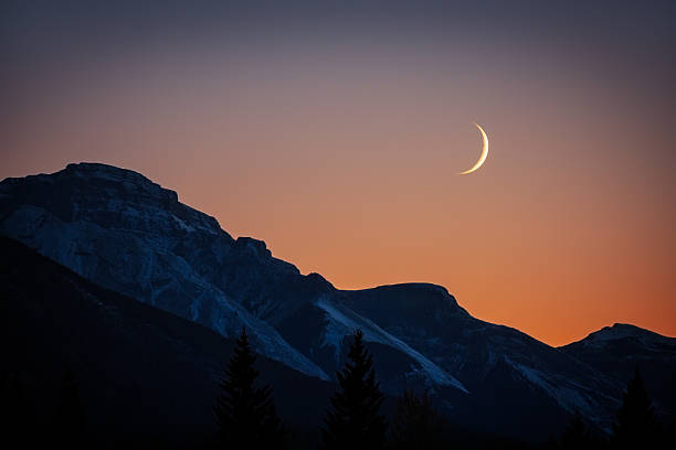 istock Crescent Moon Illuminating Rocky Mountain Silhouette at Dusk 2223422795