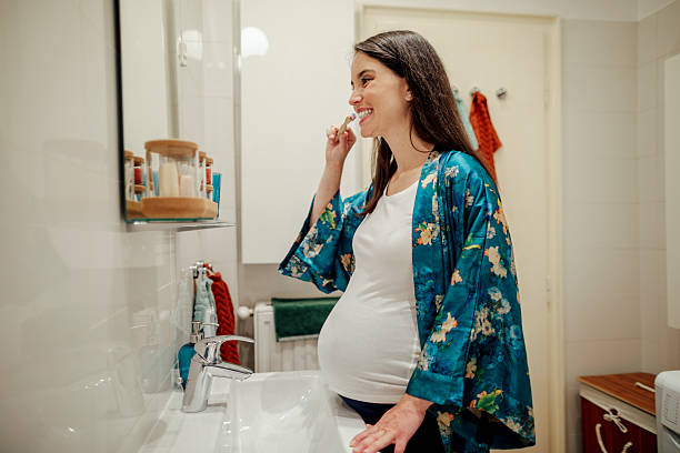 istock At home - young woman brushing her teeth 2223424663