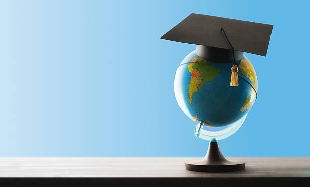 istock Study abroad concept with globe and mortarboard on wooden table 2223425015