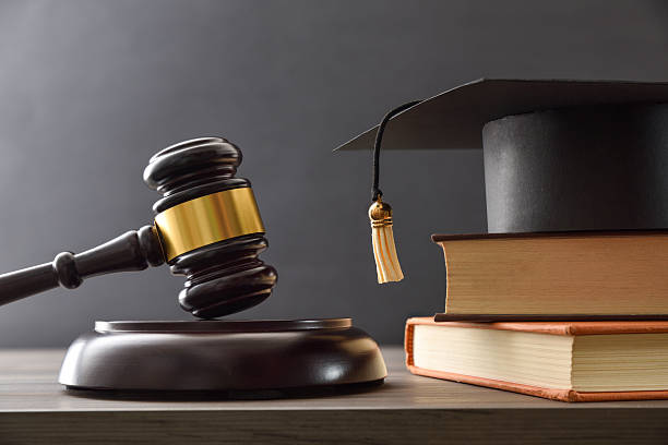 istock Educational trial with gavel, books, and mortarboard isolated on black 2223425016