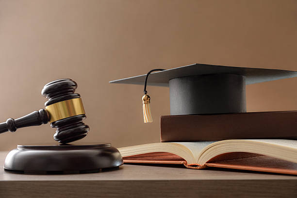 istock Educational trial with gavel, books, and mortarboard isolated on brown 2223425017