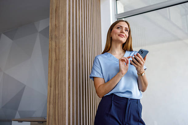 istock Businesswoman using smartphone and looking away in modern office 2223425058