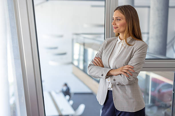 istock Confident businesswoman standing by office window 2223425090