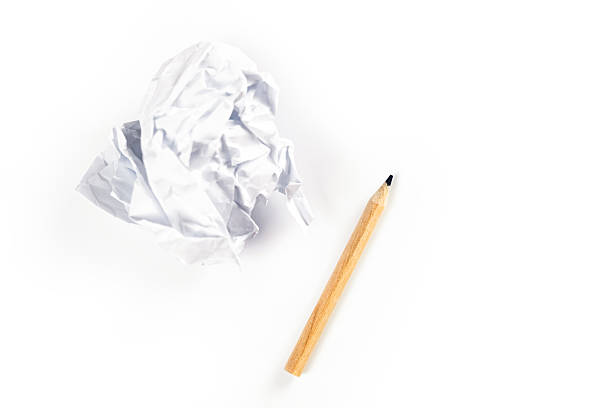 Close up of broken pencil and crumpled paper on the white surface