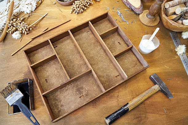 istock Handmade wooden organizer with multiple compartments in the process of being assembled. Tools, nails, glue, and dried flowers lie scattered on a rustic craft table. DIY project in progress 2223426216
