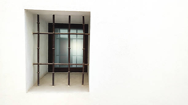 istock A small window with iron bars set in a white wall. The glass is partially visible, creating a contrast with the surrounding surface 2223427969