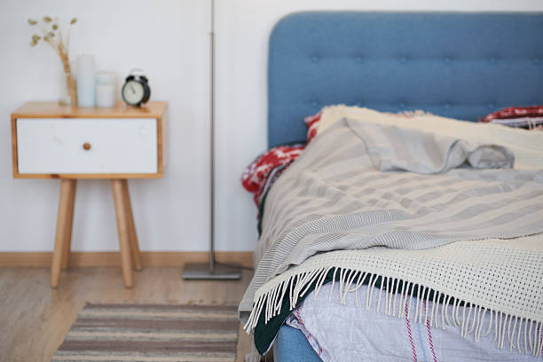 White flowers and books on a side table near a bed. Fresh design