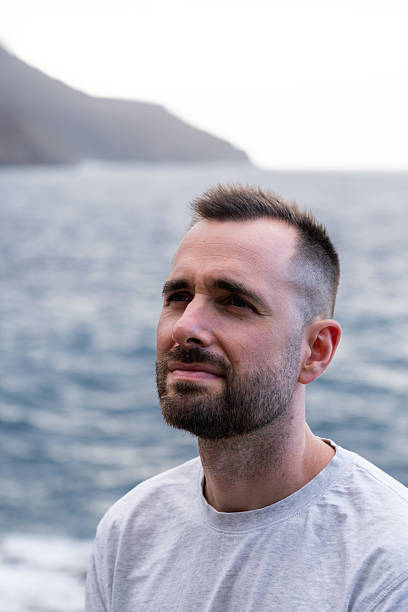 Portrait of a thoughtful young man looking up, embracing the serene atmosphere by the sea