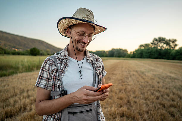 istock Smiling Farmer Using a Smartphone in a Scenic Rural Field 2223429042