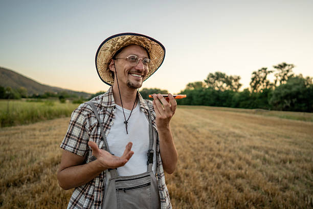 istock Smiling Farmer Using Phone for Voice Message in Scenic Rural Field 2223429043