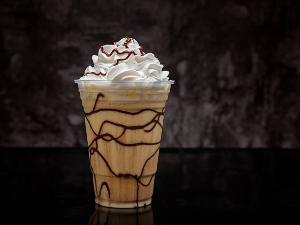 istock Vanilla milkshake with chocolate syrup in clear glass on dark background. 2223429094
