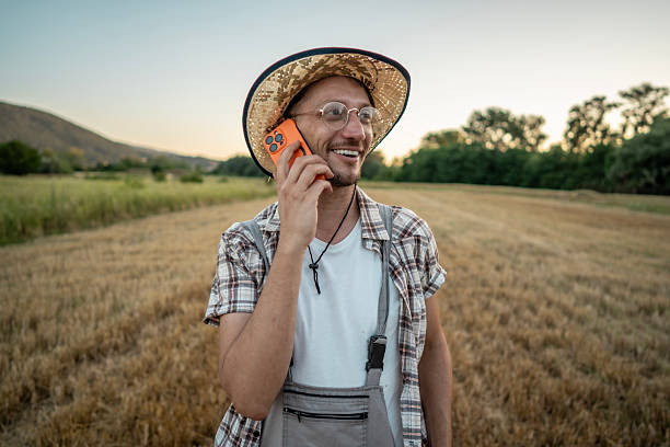 istock Man in Straw Hat Smiling While Talking on Phone in Field 2223429479