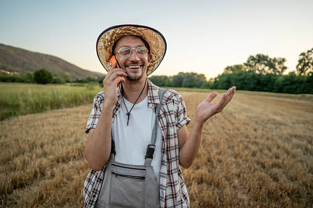 Happy Farmer Talking on Mobile Phone in a Sunlit Field