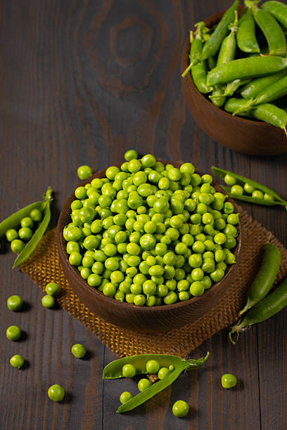 istock Fresh green peas in a bowl on a wooden table. 2223429533